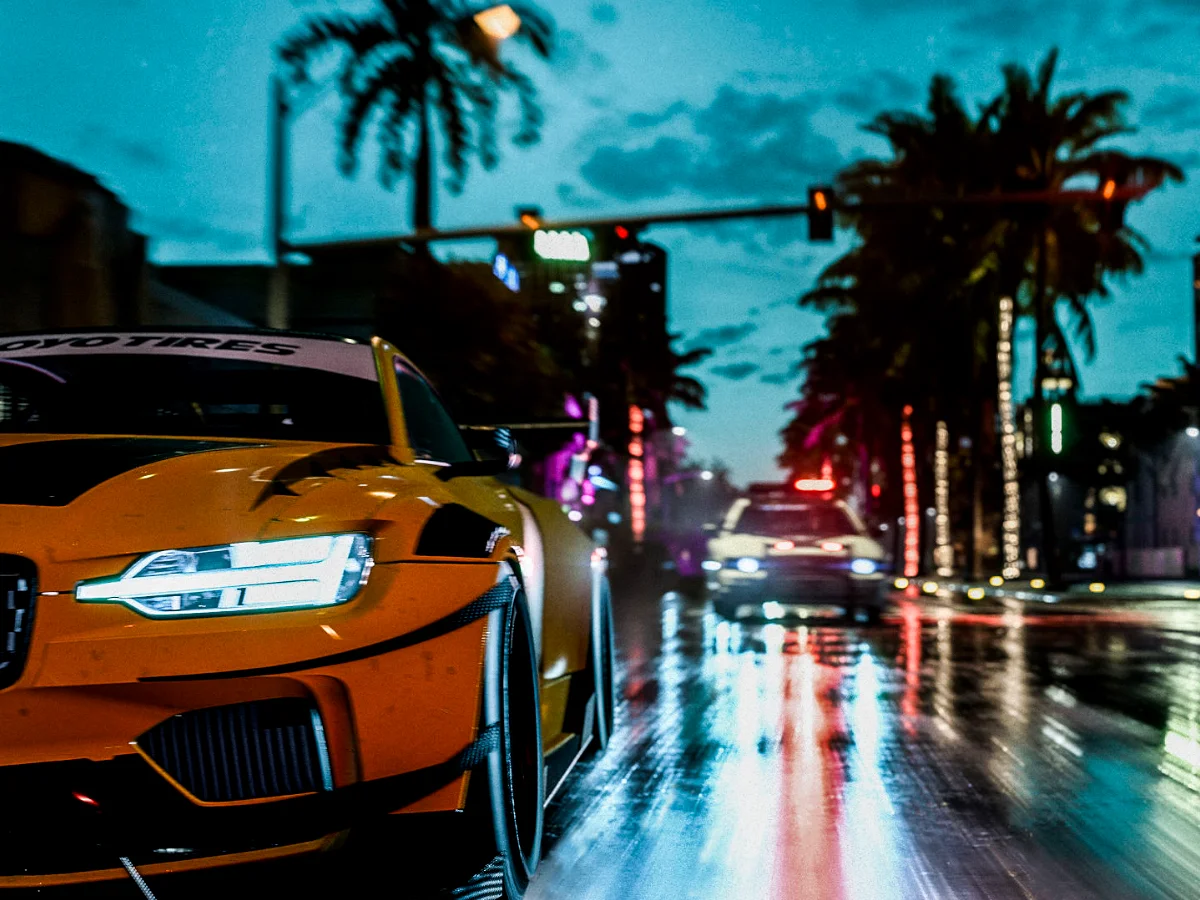 An orange car being chased by a Police car on a wet street